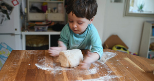 孩子在厨房帮忙在撒了面粉的表面上揉捏比萨面团11秒视频