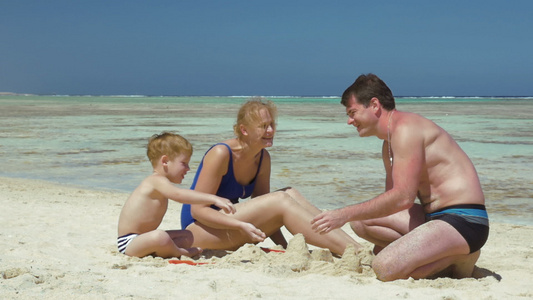 父母和儿子在沙滩上玩沙子视频