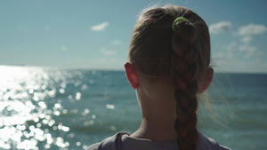 看日落和闪闪发光的海水的金发小女孩的特写10秒视频