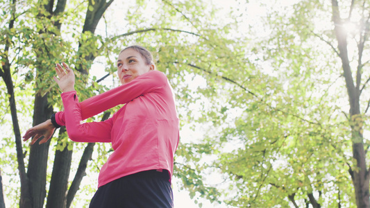 身体健康的女孩在公园中伸展她的手臂和颈部,在跑步前将运动加热起来视频