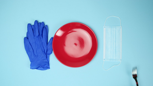 蓝色背景的手套和红色陶瓷碗和口罩上的刀叉视频