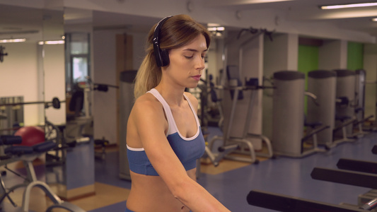 女运动员使用心血管机通过耳机收听播放列表视频
