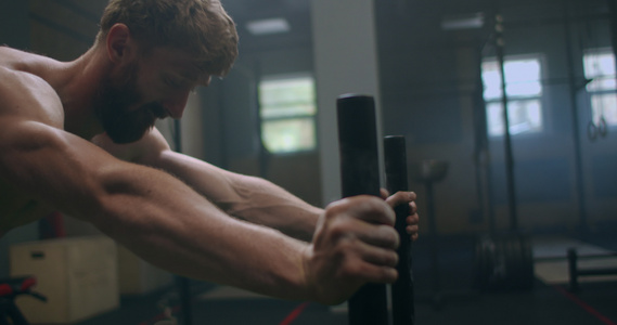 在运动慢动作期间,肌肉男在健身房推雪橇视频