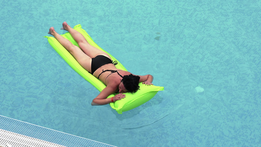 女孩在游泳池中游泳 在绿色的充气床垫上视频