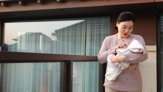 黄昏阳台上抱婴儿的女性视频