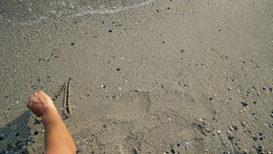 用手写一个字 古石在沙滩上被海浪冲洗视频