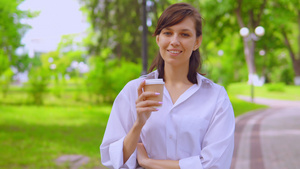 穿着白衬衫的年轻女子在夏季街头散步,喝咖啡(夏天)9秒视频