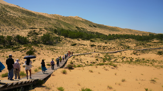 新疆西北边境大漠戈壁鸣沙山上行走的游客4k素材视频