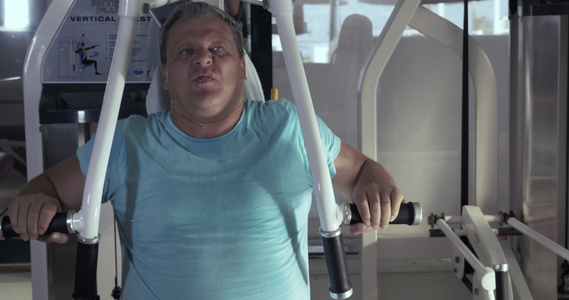 健身房成年男子近身锻炼胸口压板视频