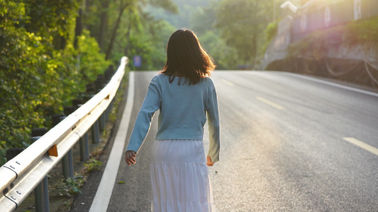 黄昏夕阳下公路上行走的女孩背影视频