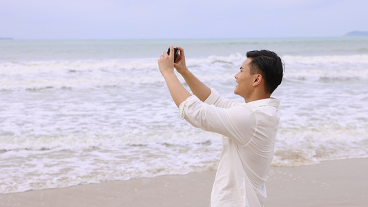 海边使用手机拍照的男青年[品牌手机]视频