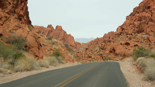公路旅行，在美国内华达州拉斯维加斯的火谷驾驶汽车。在美国搭便车旅行，公路旅行。红色外星岩层，莫哈韦沙漠荒野看起视频