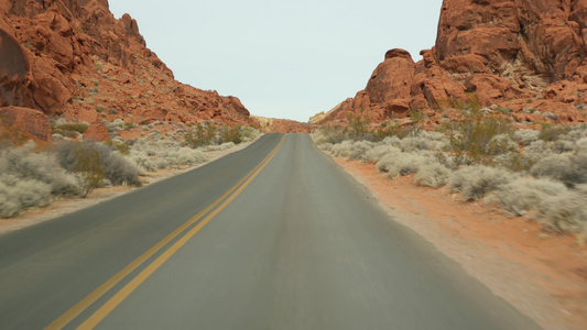 公路旅行，在美国内华达州拉斯维加斯的火谷驾驶汽车。在美国搭便车旅行，公路旅行。红色外星岩层，莫哈韦沙漠荒野看起视频