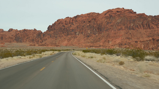 公路旅行，在美国内华达州拉斯维加斯的火谷驾驶汽车。在美国搭便车旅行，公路旅行。红色外星岩层，莫哈韦沙漠荒野看起视频