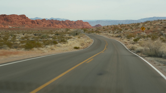 公路旅行，在美国内华达州拉斯维加斯的火谷驾驶汽车。在美国搭便车旅行，公路旅行。红色外星岩层，莫哈韦沙漠荒野看起视频