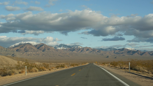 公路旅行，驾驶汽车从死亡谷到美国内华达州拉斯维加斯。在美国搭便车旅行。公路之旅，戏剧性的气氛，云，山和莫哈韦沙视频