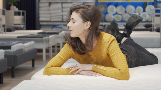 在家具店里尝试整形床垫的可爱女人视频