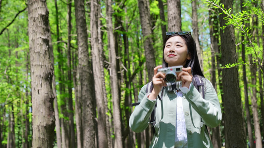 户外美女在用相机拍摄森林公园的美景视频