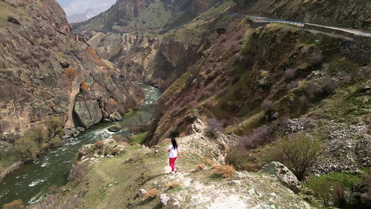 蓝褐发女孩享受着不可思议的自然景观 山谷地貌在悬崖上 悬崖俯视山谷视频