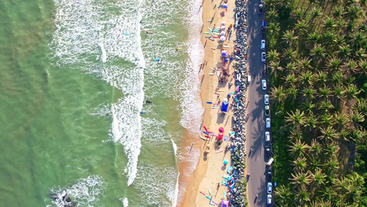 海南省万宁市日月湾阳光下的大海沙滩椰树以及在海面上冲浪的青春少年与美女视频