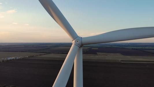 关闭风力涡轮机旋转转子叶片的细节与背景的农田。可再生能源风车电力生产生态视频