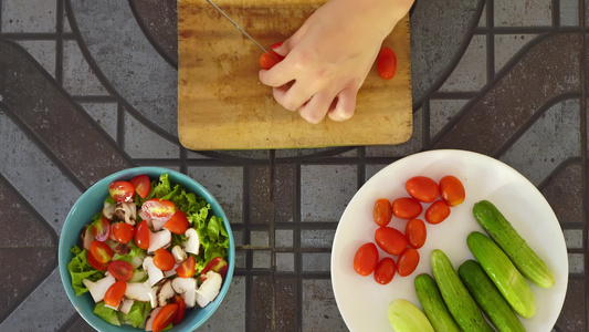 顶视图的人在厨房桌子上切新鲜蔬菜做沙拉。切西红柿。用新鲜蔬菜制作维生素沙拉视频