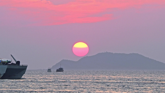 海南三亚橘红色夕阳晚霞下行驶的巨型豪华游艇视频