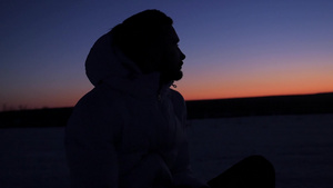 一个戴着兜帽的年轻男子坐在日落下深思熟虑9秒视频