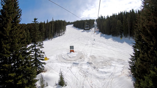 在阳光明媚的日子里，从椅子滑雪缆车上与滑雪者在蓝天上的 POV，滑雪者在慢动作中滑下赛道视频