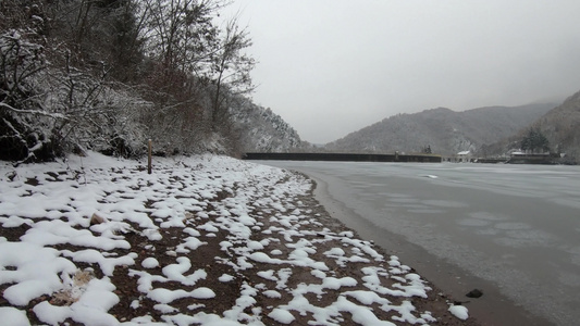 在雪中走在冰冻湖旁边的岸边上视频