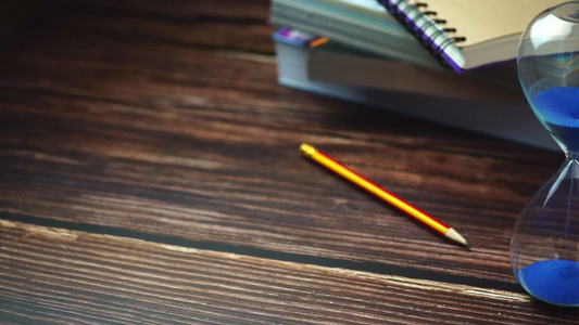 装铅笔和书架在木制桌上的慢动作时空玻璃板视频