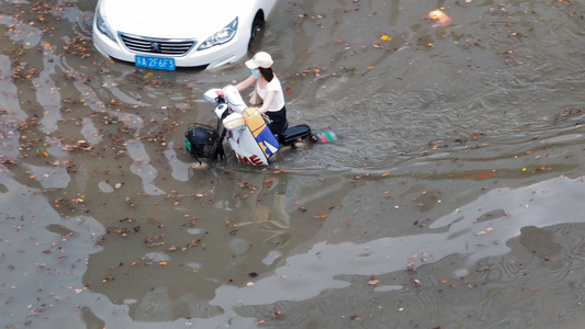 4K航拍城市道路积水美女骑电动车过水水淹洪涝视频