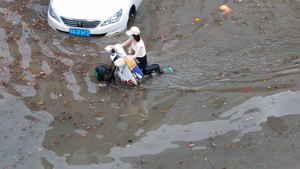 4K航拍城市道路积水美女骑电动车过水水淹洪涝25秒视频