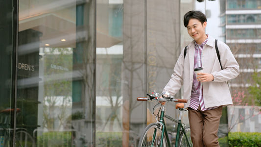 都市男青年拿着咖啡推行自行车视频
