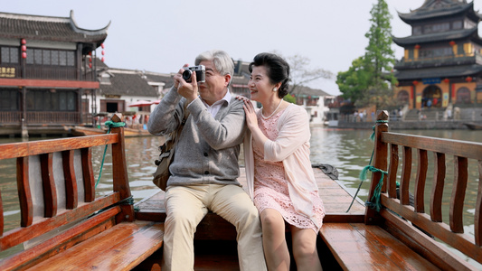 老年夫妇坐在人力船上拍照视频