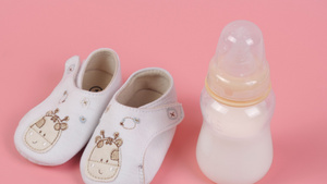 粉色背景婴儿鞋和小奶瓶可爱组合19秒视频