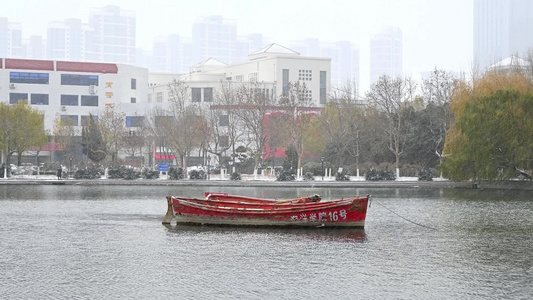 冬天大雪纷飞湖泊上的红船视频