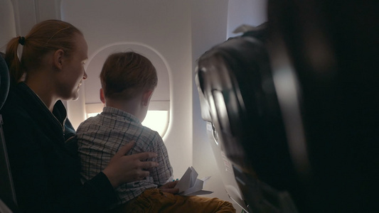 男孩和母亲透过飞机窗向外看视频
