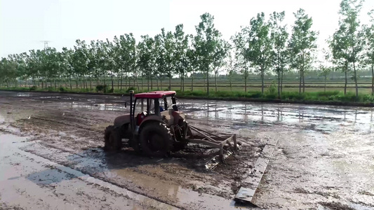航拍大型拖拉机在水稻田平整土地视频