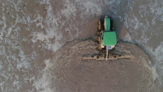 航拍大型拖拉机在水稻田平整土地视频