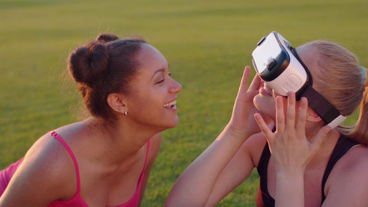 两个年轻女性坐在草坪上体验vr眼镜视频