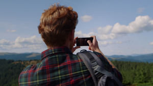 年轻男性在山顶上拿手机拍摄自然风光17秒视频