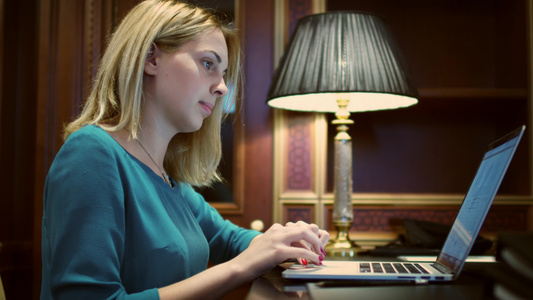 桌子前打开笔记本电脑认真工作的年轻女性视频
