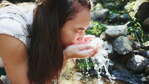 捧起溪水洗脸的年轻女性12秒视频