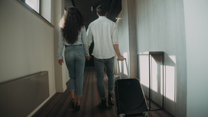 在走廊拉着行李箱的情侣年轻夫妇在酒店牵手17秒视频