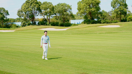 男青年手握高尔夫球杆走在球场上视频