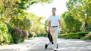 年轻男性拉着高尔夫器材走在路上8秒视频