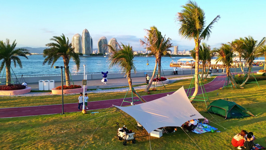 海南三亚春季小洲岛复绿公园阳光草坪上的露营放风筝的开兴市民游客与家人视频