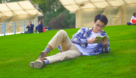 男青年趴在公园草地背单词视频