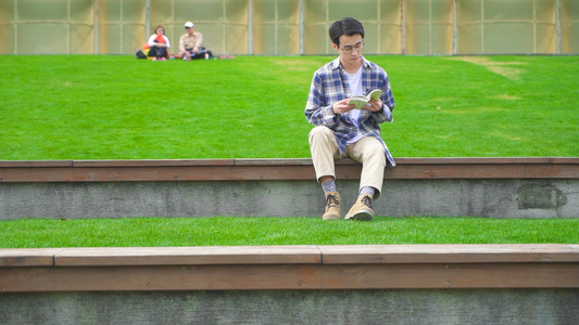 男青年坐在公园看书视频
